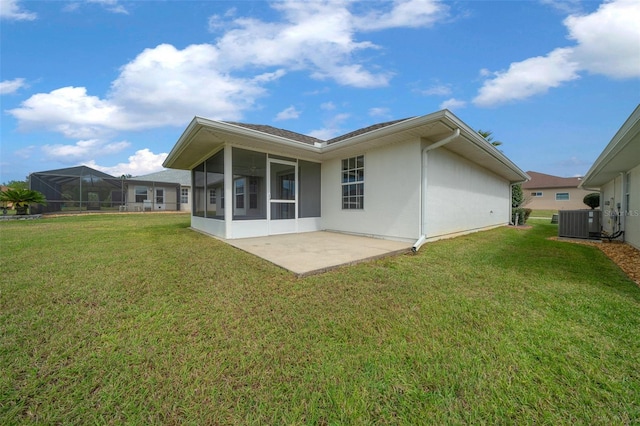 back of house featuring a lawn, a sunroom, a patio area, central AC, and stucco siding