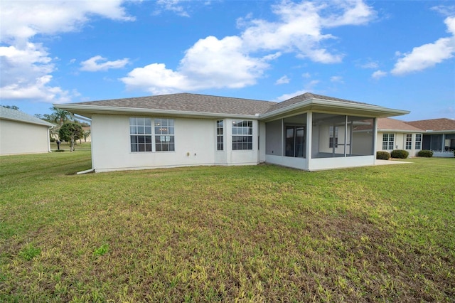 rear view of house featuring a sunroom, a lawn, and stucco siding