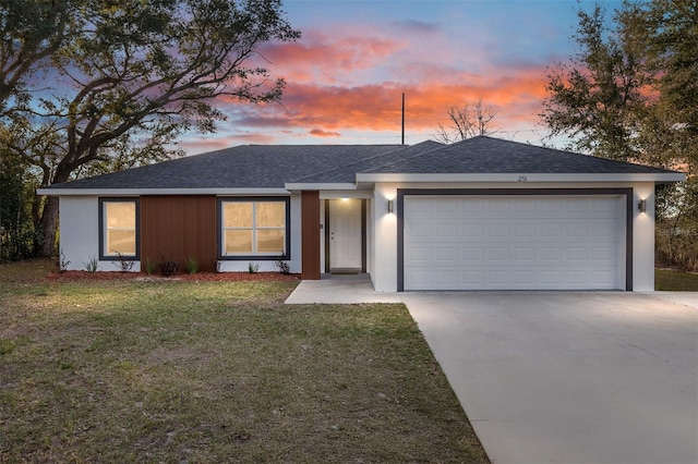 ranch-style house featuring a front yard, concrete driveway, roof with shingles, and an attached garage