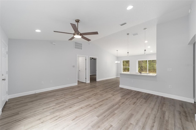 unfurnished living room featuring a sink, visible vents, baseboards, vaulted ceiling, and light wood-type flooring