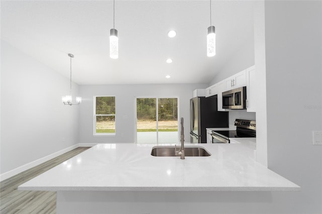 kitchen featuring white cabinets, lofted ceiling, appliances with stainless steel finishes, light wood-style floors, and a sink