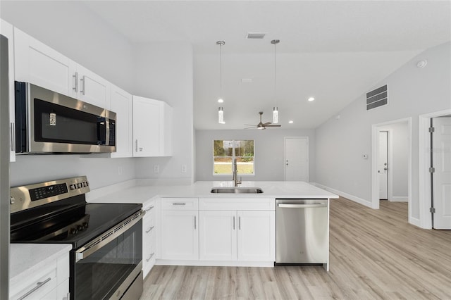 kitchen with a peninsula, appliances with stainless steel finishes, a sink, and visible vents