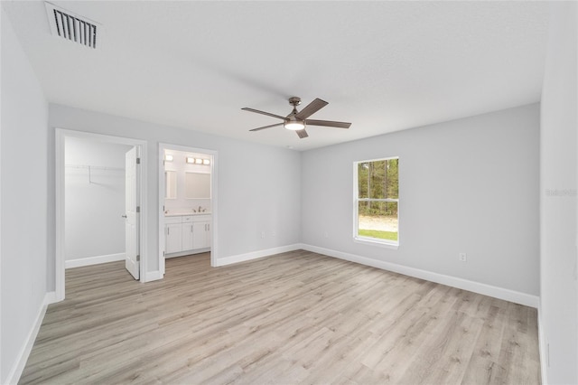 unfurnished bedroom featuring light wood-style floors, visible vents, a walk in closet, and a closet