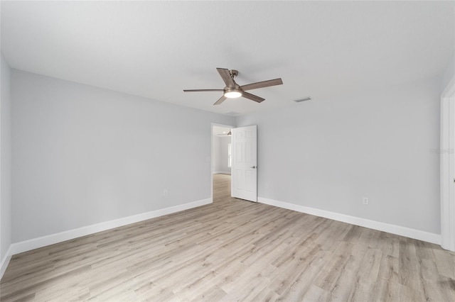 spare room featuring baseboards, visible vents, ceiling fan, and light wood finished floors