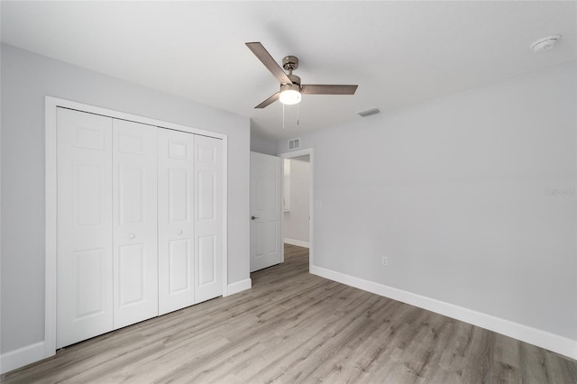 unfurnished bedroom featuring visible vents, baseboards, a ceiling fan, wood finished floors, and a closet