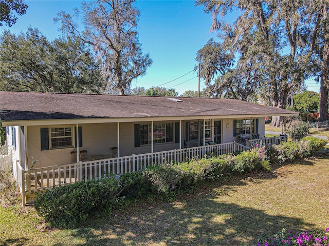 ranch-style home featuring covered porch, concrete block siding, and a front lawn