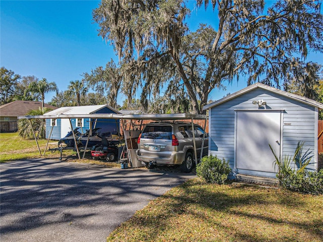 view of shed with aphalt driveway and a detached carport