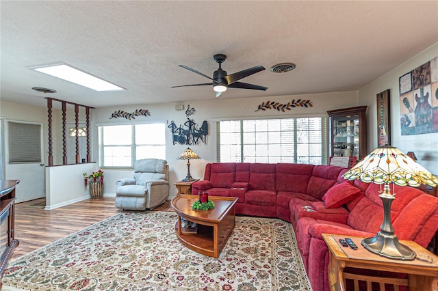 living area featuring a textured ceiling, a skylight, wood finished floors, and visible vents