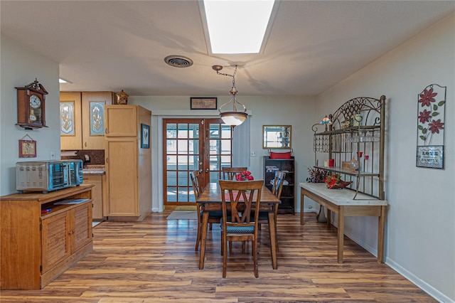 dining space featuring french doors, visible vents, baseboards, and wood finished floors