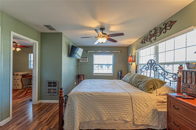 bedroom featuring a wall unit AC, visible vents, baseboards, heating unit, and dark wood-style floors