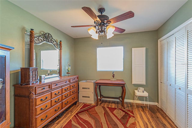 bedroom featuring dark wood-style floors, multiple windows, a closet, and baseboards