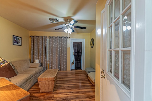 living room featuring dark wood-type flooring, visible vents, and a ceiling fan