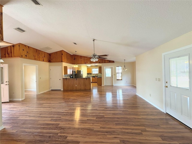 unfurnished living room featuring a textured ceiling, ceiling fan, lofted ceiling, visible vents, and dark wood finished floors