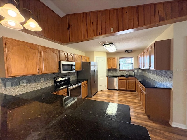 kitchen with stainless steel appliances, brown cabinets, a sink, and backsplash