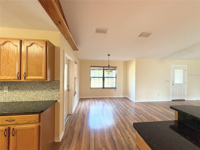 kitchen with decorative light fixtures, dark countertops, visible vents, decorative backsplash, and open floor plan