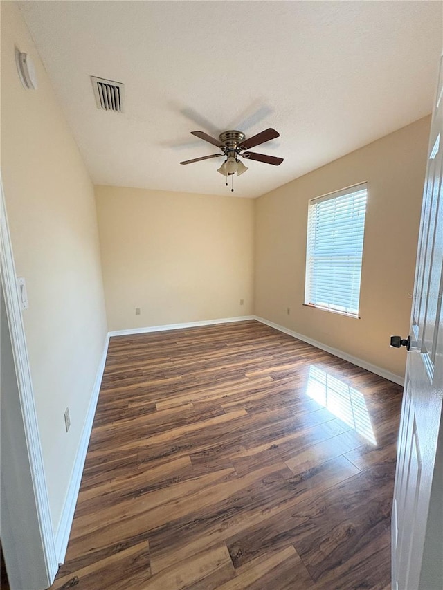 unfurnished room with baseboards, visible vents, ceiling fan, and dark wood-style flooring