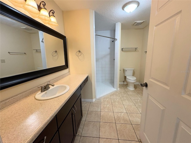 full bath with toilet, tile patterned floors, a tile shower, a textured ceiling, and vanity