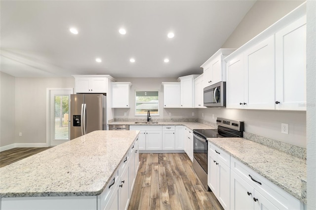 kitchen featuring appliances with stainless steel finishes, a sink, white cabinetry, and light stone countertops