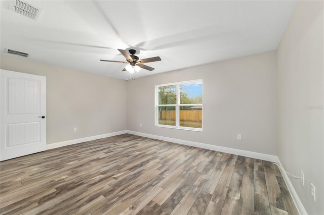 empty room featuring baseboards, visible vents, ceiling fan, and wood finished floors