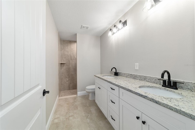 bathroom with toilet, a sink, baseboards, and double vanity