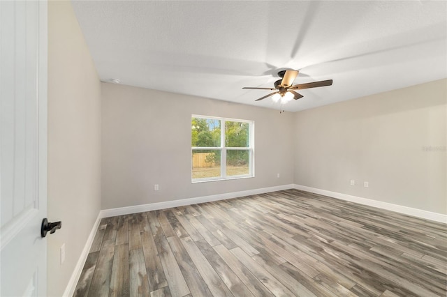 spare room featuring wood finished floors, a ceiling fan, and baseboards