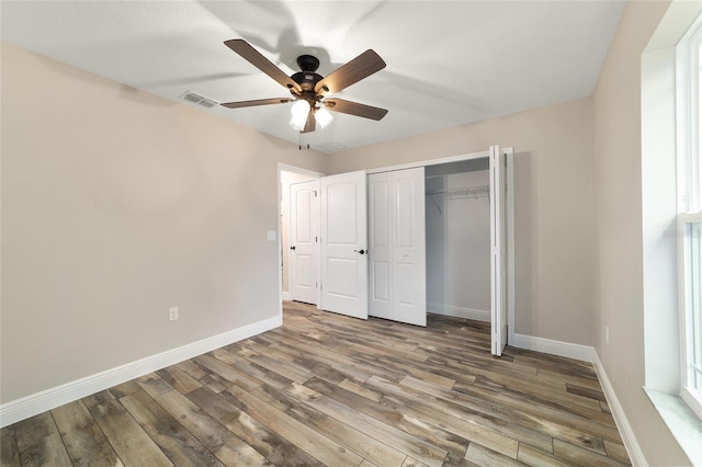 unfurnished bedroom with a closet, wood finished floors, visible vents, and baseboards