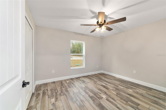 unfurnished room with ceiling fan, wood finished floors, and baseboards