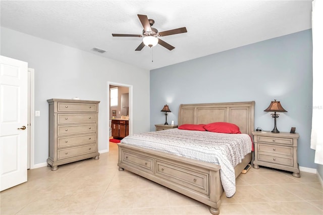 bedroom with light tile patterned floors, ensuite bathroom, visible vents, and baseboards