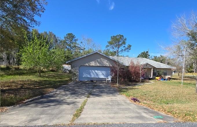 single story home featuring concrete driveway, an attached garage, and a front yard