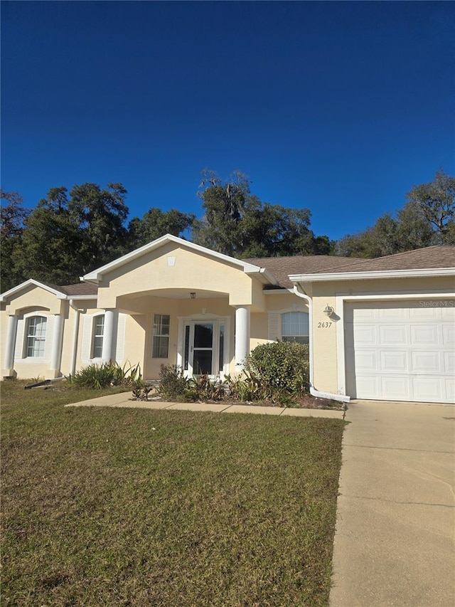 view of front of property with a garage, a front lawn, and stucco siding