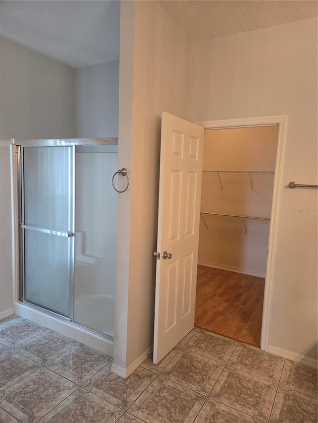 full bathroom with a stall shower and baseboards