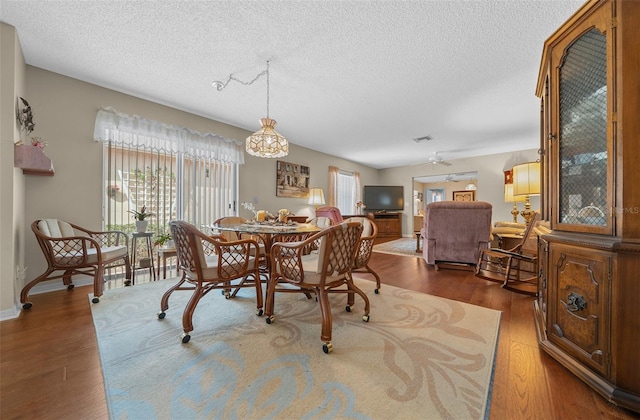 dining room featuring a textured ceiling, dark wood-type flooring, and visible vents