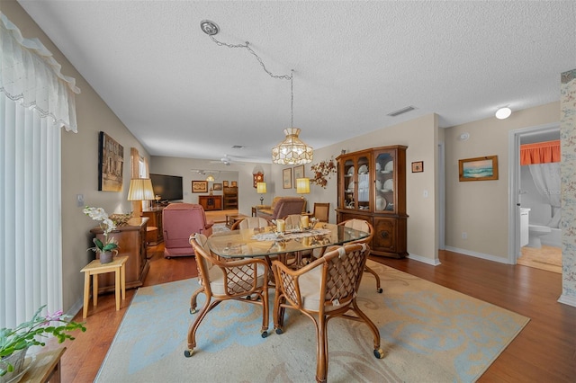dining area featuring visible vents, a textured ceiling, baseboards, and wood finished floors