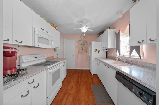 kitchen featuring light countertops, white cabinets, a sink, a textured ceiling, and white appliances