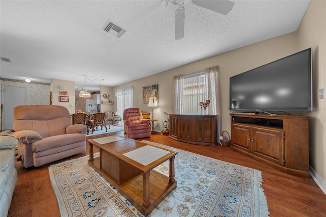 living room with a textured ceiling, wood finished floors, and visible vents