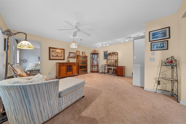 living area with light carpet, track lighting, baseboards, and a ceiling fan