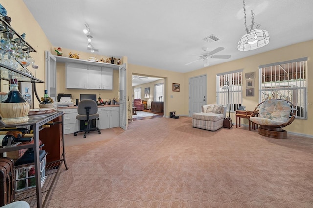 interior space with light carpet, ceiling fan, built in study area, and visible vents