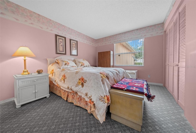 bedroom featuring a closet, dark carpet, a textured ceiling, and baseboards