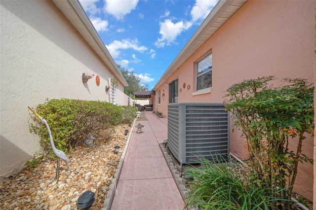 view of side of property with a patio area, cooling unit, and stucco siding