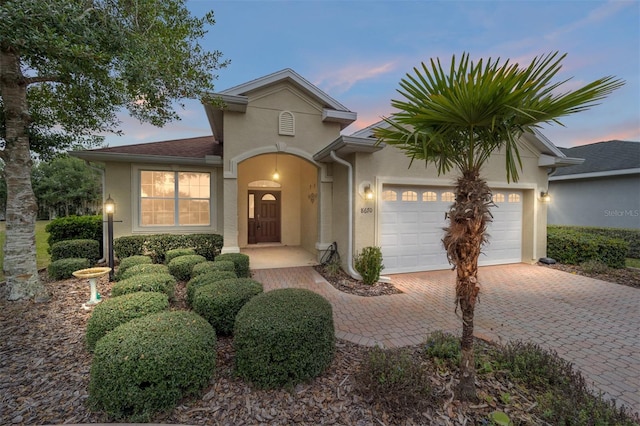 view of front of home featuring decorative driveway, an attached garage, and stucco siding