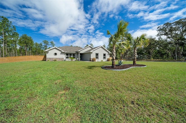 view of front of house with stone siding, fence, a front lawn, and stucco siding