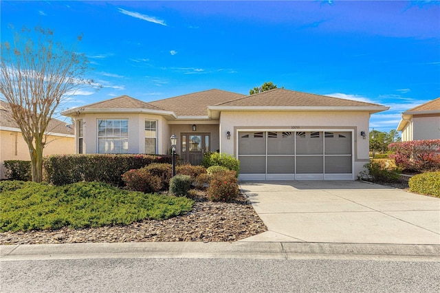 view of front of home with a garage, roof with shingles, concrete driveway, and stucco siding