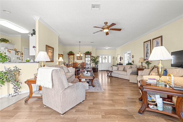 living area with light wood finished floors, visible vents, ceiling fan, ornamental molding, and a textured ceiling