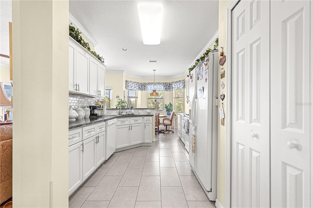 kitchen featuring a peninsula, white appliances, white cabinetry, hanging light fixtures, and ornamental molding