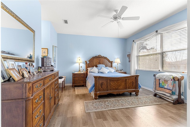 bedroom featuring ceiling fan, wood finished floors, visible vents, and baseboards