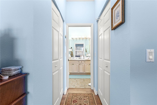 hallway featuring wood finished floors and a textured wall