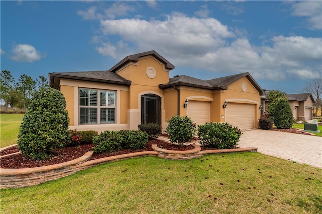 view of front of property with a garage, a front yard, decorative driveway, and stucco siding