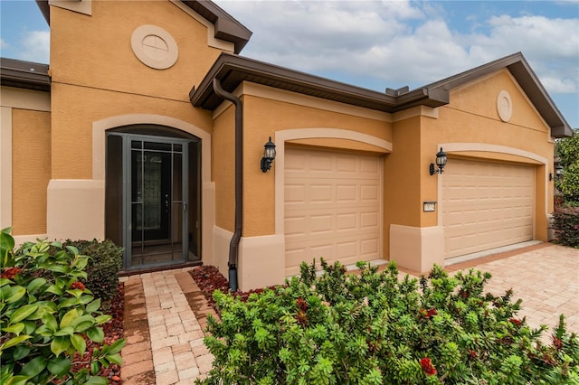 exterior space with an attached garage, decorative driveway, and stucco siding