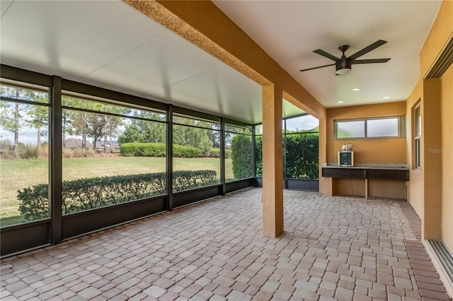 unfurnished sunroom featuring a ceiling fan and a wealth of natural light