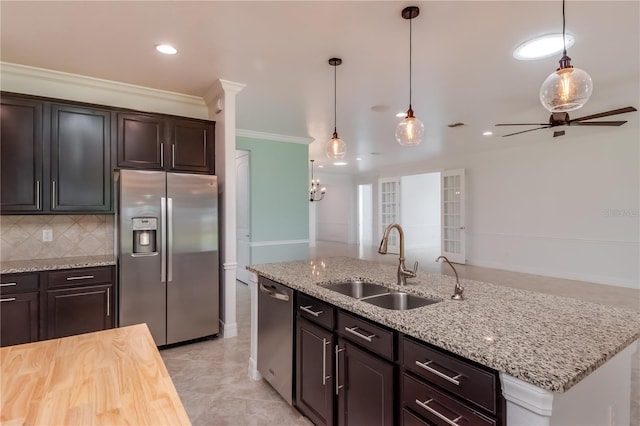 kitchen featuring crown molding, stainless steel appliances, a sink, backsplash, and pendant lighting